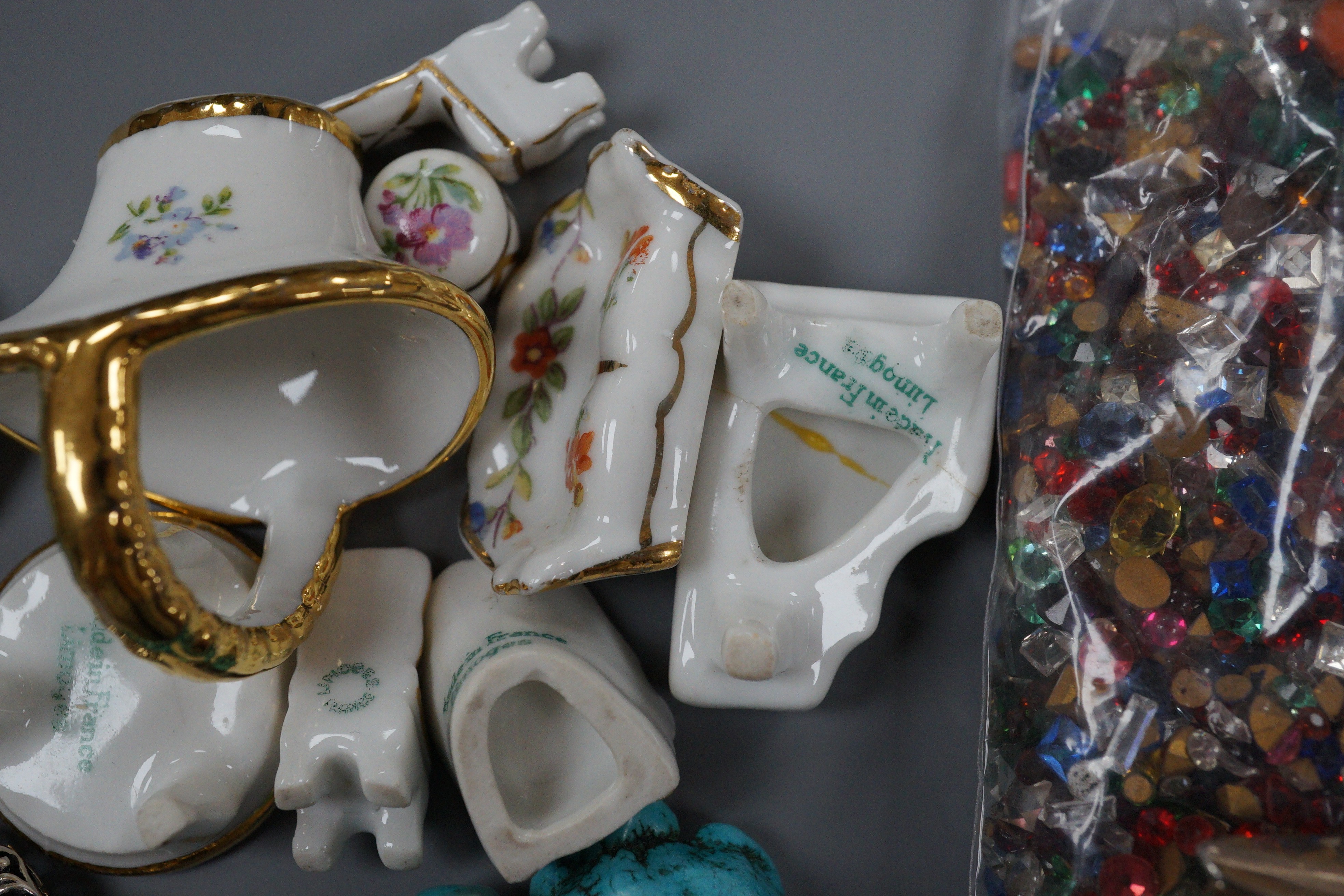 Nine miniature items of Limoges, including furniture, three turquoise necklaces, a group of assorted loose coloured paste stones and four assorted lighters.